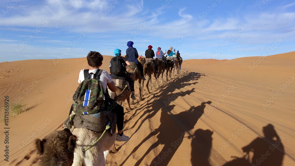 Caravan going through the sand dunes in the Sahara Desert, Morocco - Merzuga - tourist visit the desert on camels during the holidays - adventure and freedom during a trip , safari - organized travel