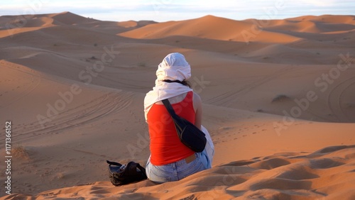 Obraz na płótnie tourist girl with turban looking the beauty of the sand dunes of the Sahara Africa desert in Morocco in Merzouga, meditation and love for nature, relax and inspirazione during a travel Journey w salonie