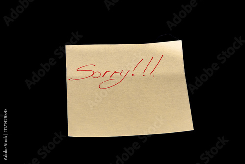 Yellow adhesive paper, similar to a Post-it note, on a black background with the word 