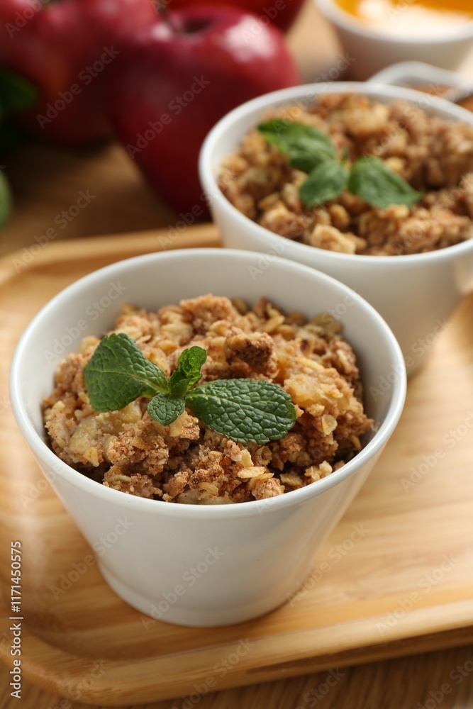 Delicious apple crisp with mint in bowls on table, closeup Delicious apple crisp with mint in bowls on table, closeup