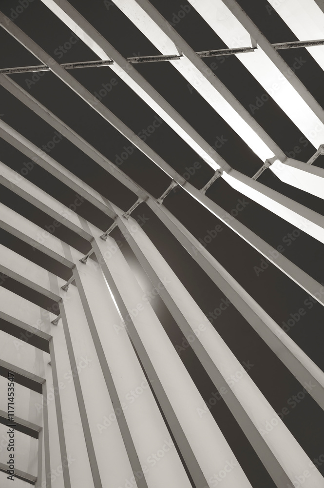 Naklejka premium Beautiful geometric abstraction of parallel non-intersecting metal columns and elements with a light source from behind. Vertical photo