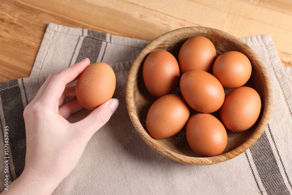 Woman with raw eggs at wooden table, top view Woman with raw eggs at wooden table, top view