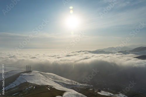 On the slopes of Chatkal Range near Angren, the city is completely covered in clouds and the sun shines above. photo