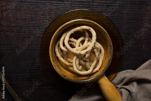 Top view of fried corn rings snack in a brown ceramic bowl, Overhead view of nigerian kokoro egba corn snack on a chopping board photo