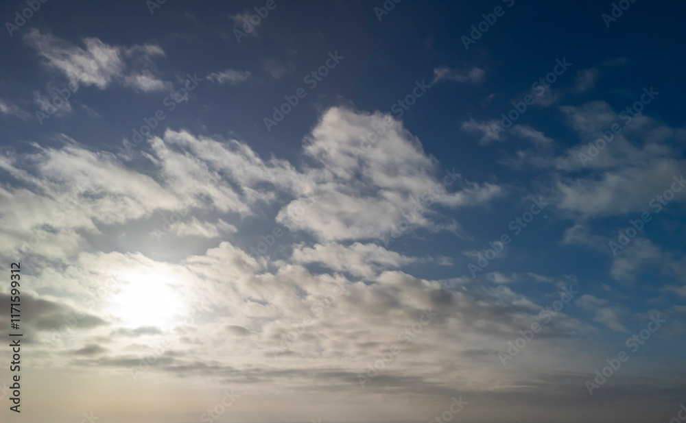 A beautiful sky filled with fluffy clouds against a vibrant blue backdrop, with the sun shining through, creating a serene atmosphere A beautiful sky filled with fluffy clouds against a vibrant blue backdrop, with the sun shining through, creating a serene atmosphere