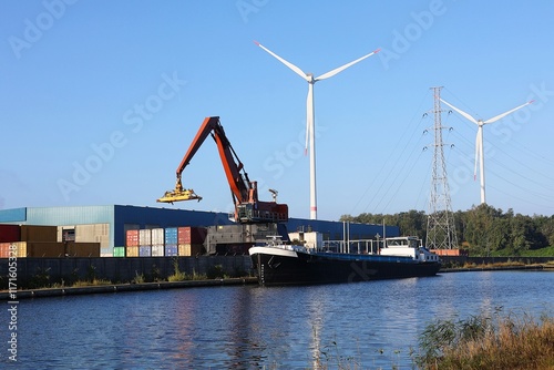 Container crane, containers and barge on the Kempisch Canal, Belgium. Industrial transport via waterway.
