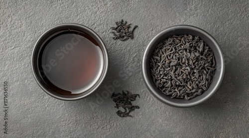 Black tea served in a cup with fresh tea leaves and loose tea on a dark surface