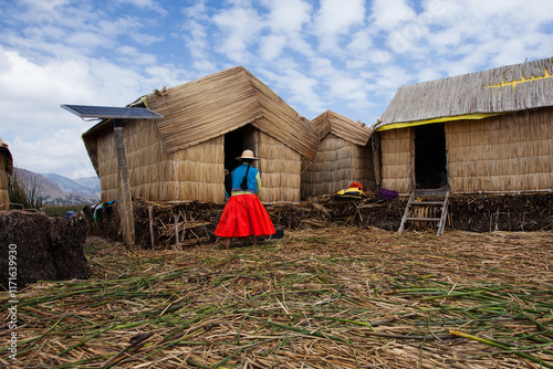 Tableau sur toile Uros woman wearing traditional costume in Titicaca lake with traditional housing