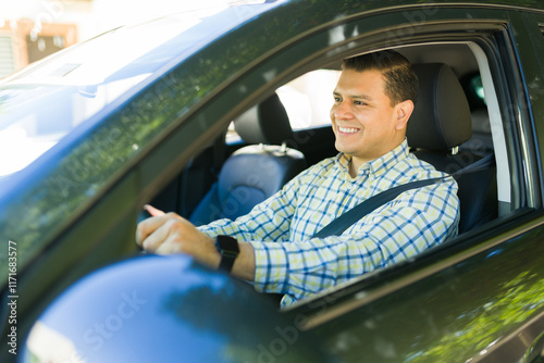 Happy hispanic man wearing a seatbelt while driving to work in his car photo