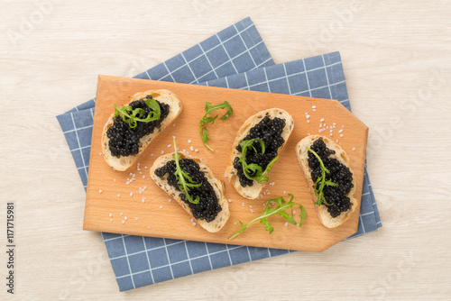 Bread slice with black caviar served on on wooden background, top view photo