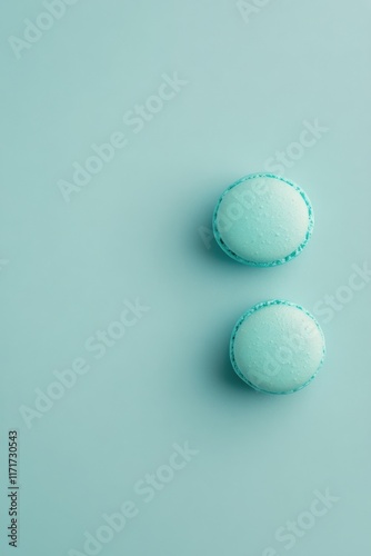 Blue macarons arranged on a pastel surface creating a visually appealing dess...