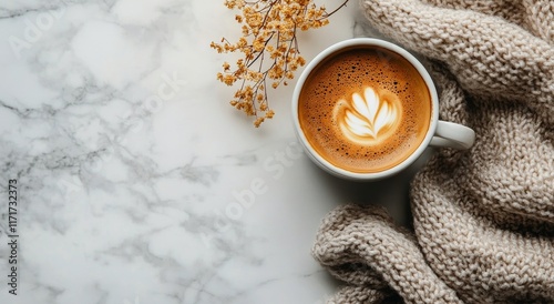 Latte art in a white cup on marble table with green leaves in the background