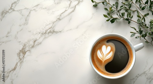 Latte art in a white cup on marble table with green leaves in the background