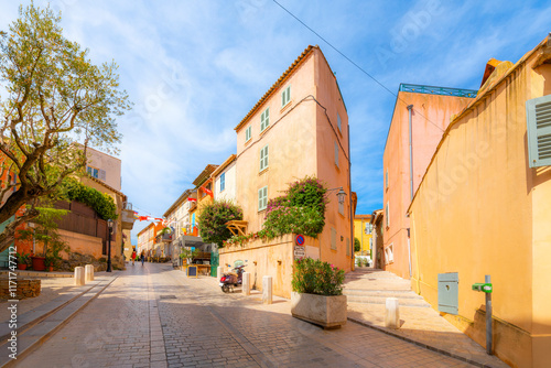 Fototapeta Naklejka Na Ścianę i Meble -  Colorful shops and cafes line the narrow, hilly alleys and streets in the old town of Saint-Tropez, France, along the Cote d'Azur French Riviera.