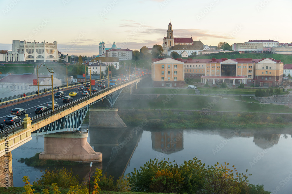 Obraz premium Panoramic view of the city on a sunny summer day. A road bridge crosses the river in the city.