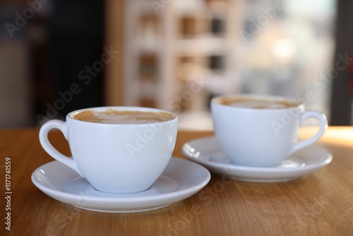 Cups of aromatic coffee on wooden table in cafe, closeup