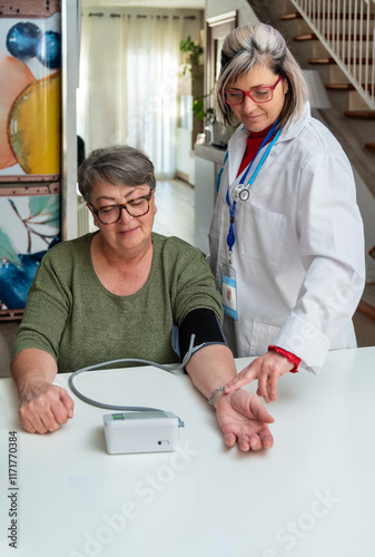 Female doctor measuring blood pressure of senior woman at home