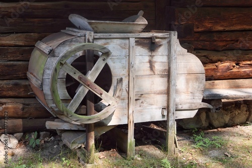 An old winnowing machine standing against the wall of a wooden house photo