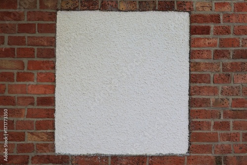 White square of plaster on a red brick wall.