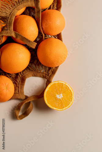 Fresh oranges in an reusable eco-friendly shopping mesh bag on light background. Zero waste and ecology