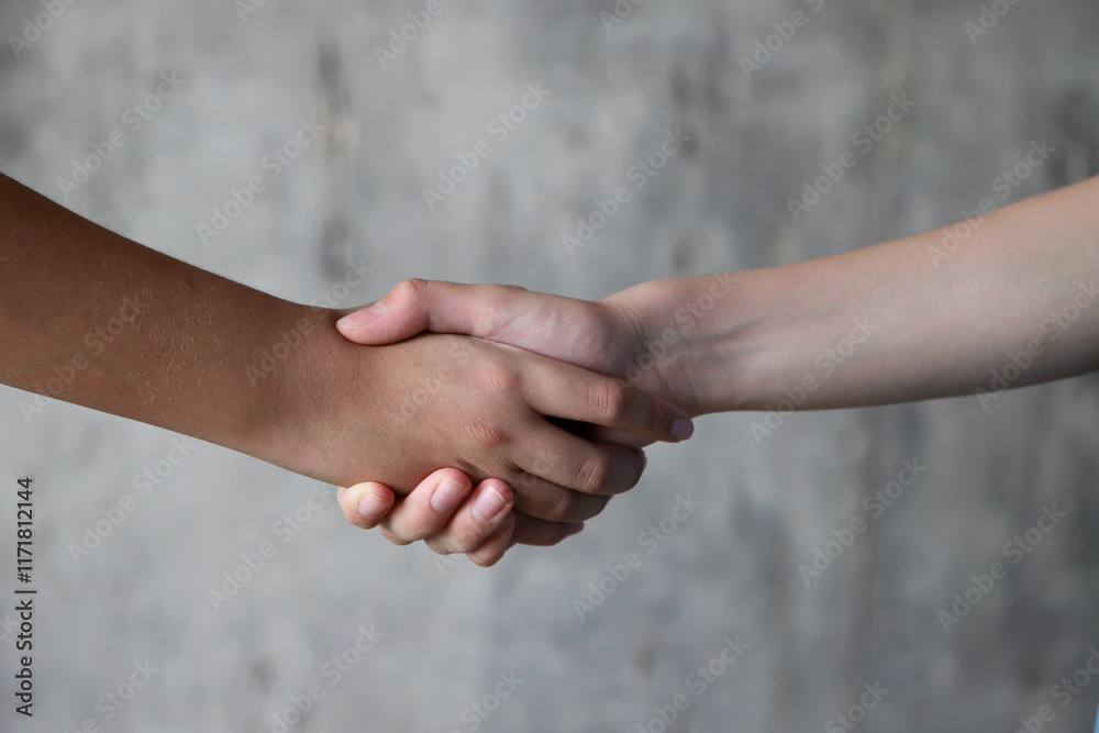 Children handshake on gray background. Two teenagers shaking hands in a gesture of agreement friendship. Children handshake on gray background. Two teenagers shaking hands in a gesture of agreement friendship.
