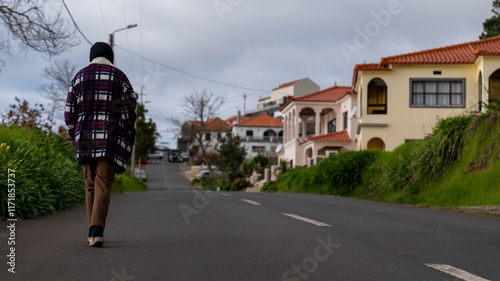 Wallpaper Mural A person walking down a quiet suburban street lined with colorful houses and greenery. The overcast sky adds a calm and reflective mood to the scene. Torontodigital.ca