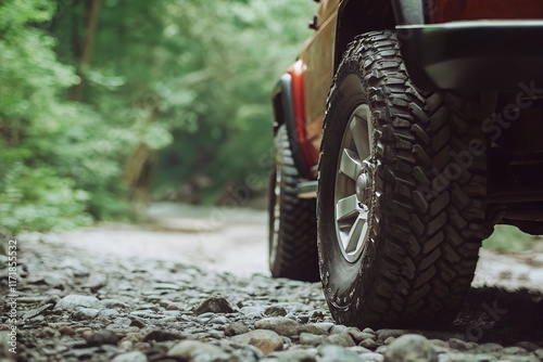 close-up of a red off-road vehicle's tire navigating rocky terrain in a lush green forest photo