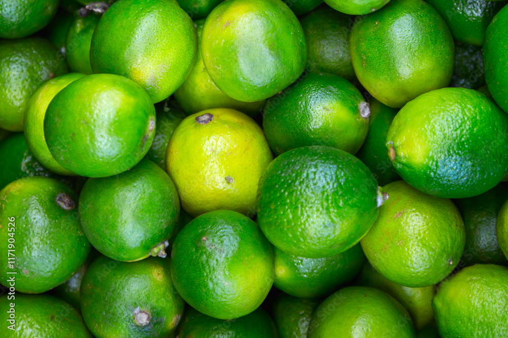 Many lime citrus fruits at a fruit market. Food background. Top view Many lime citrus fruits at a fruit market. Food background. Top view