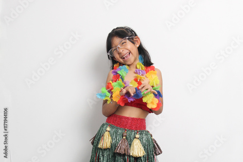 5 year old Latina brunette girl with glasses and Hawaiian skirt enjoys dancing and does Hawaii dance steps very happy and excited photo