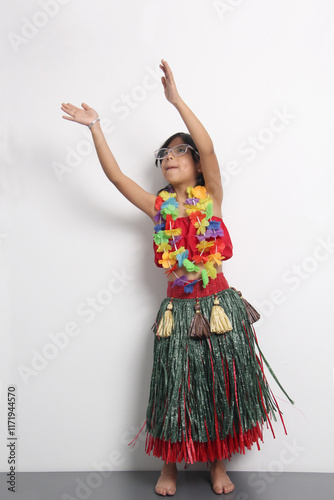 5 year old Latina brunette girl with glasses and Hawaiian skirt enjoys dancing and does Hawaii dance steps very happy and excited photo