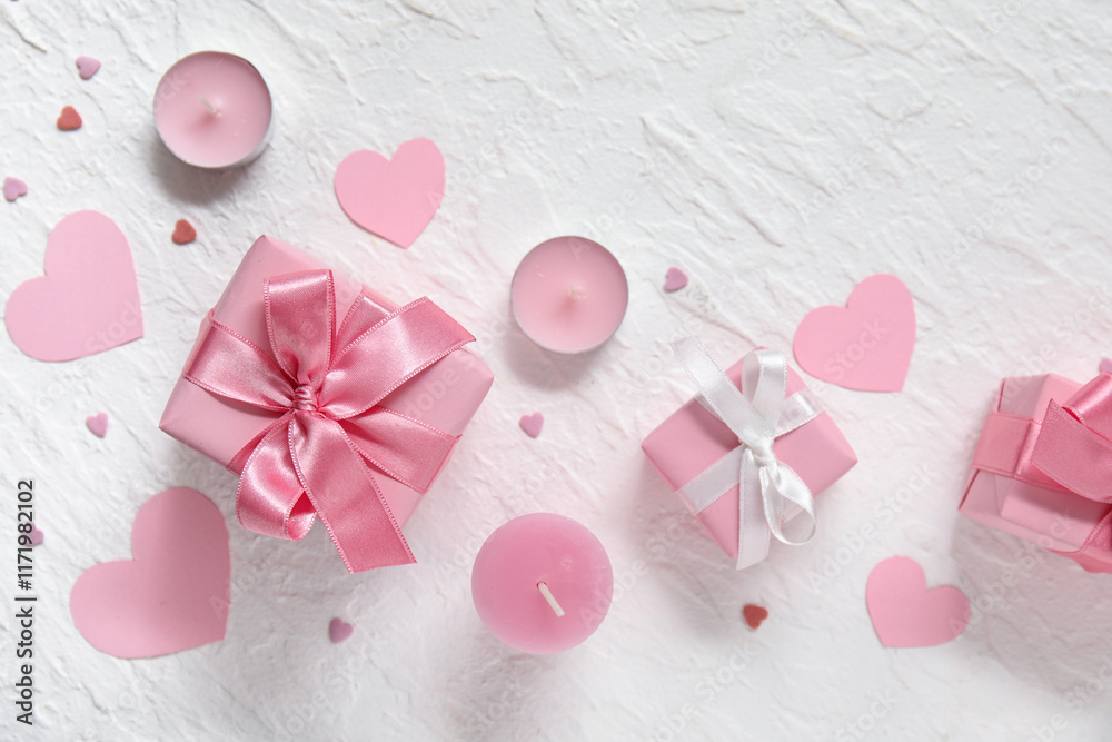 Fototapeta premium Pink gift boxes, paper hearts and candles on white grunge background. Valentine's Day celebration