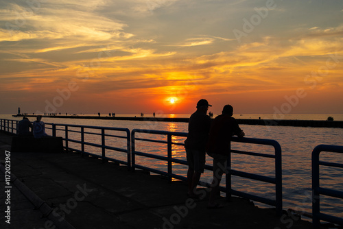 Friends talking on a peer at sunset