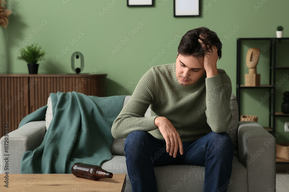 Depressed young man sitting on couch at home Depressed young man sitting on couch at home