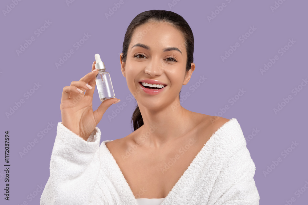 Beautiful young happy woman in bathrobe with bottle of cosmetic oil on purple background Beautiful young happy woman in bathrobe with bottle of cosmetic oil on purple background