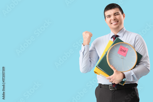 Happy businessman with clock and folders on blue background. Time management concept photo