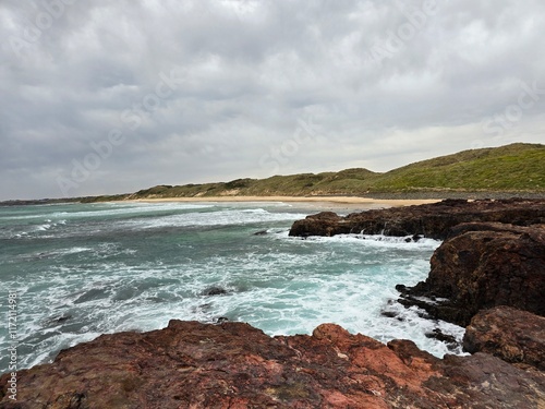 Scenic Coastal View of Forest Caves, Australia with Rocky Shoreline and Rolling Waves under Cloudy Sky