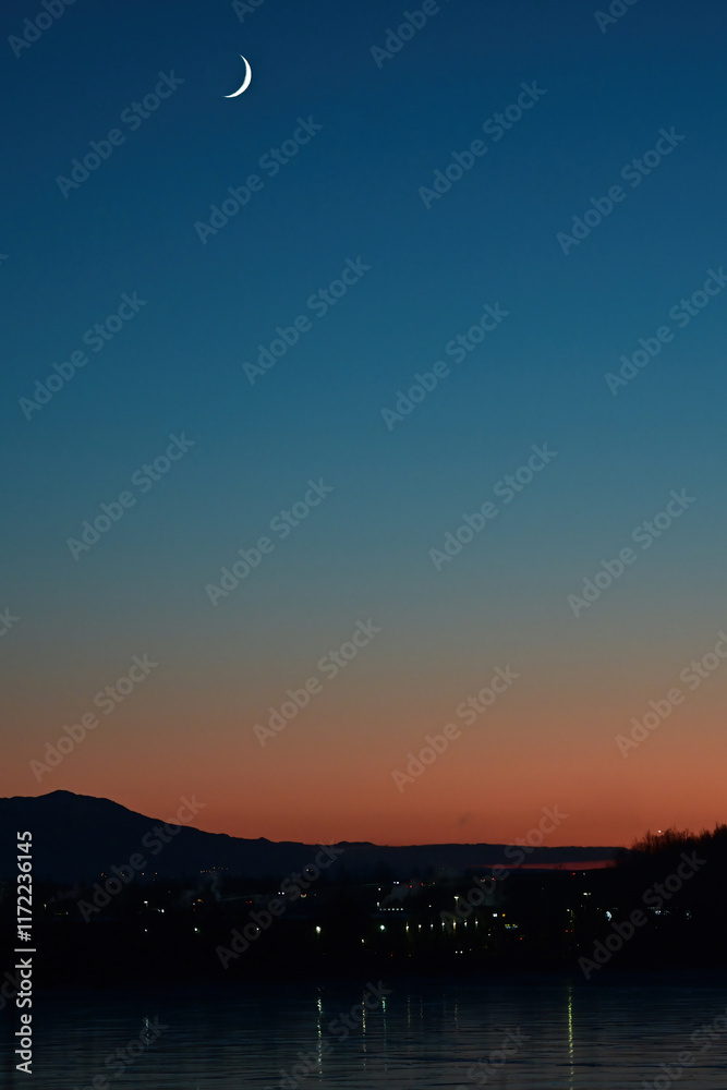 Obraz premium A fingernail moon rises over Wasilla, Alaska, at sunset.