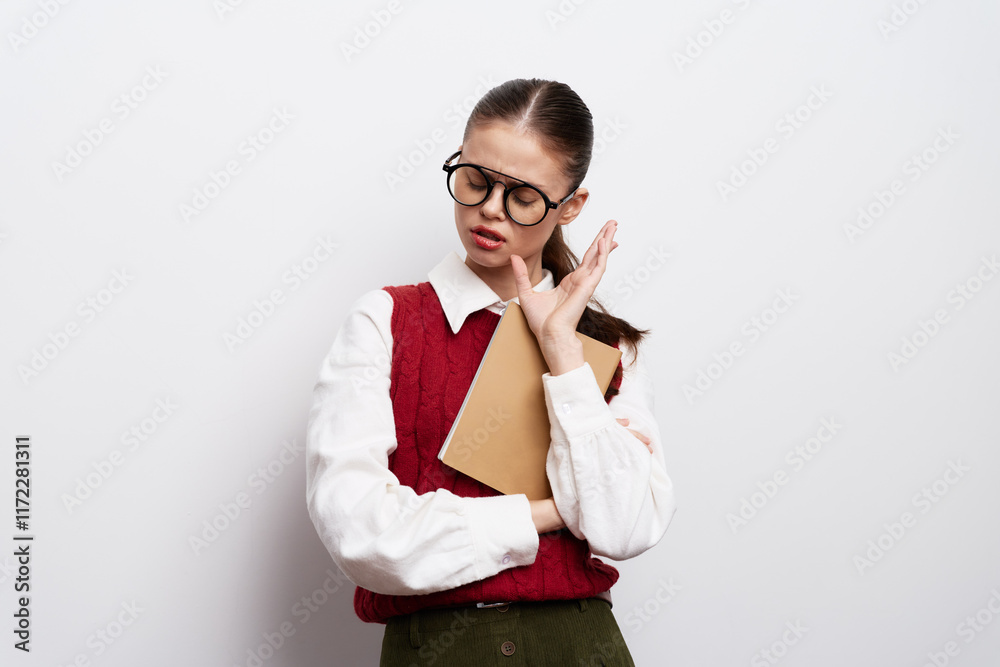 Young girl with glasses wearing a red sweater against a white background, holding a notebook, displaying a thoughtful expression, embodying a student archetype Young girl with glasses wearing a red sweater against a white background, holding a notebook, displaying a thoughtful expression, embodying a student archetype
