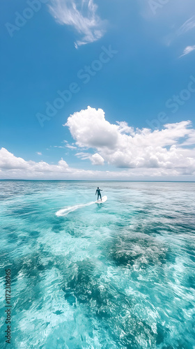 Man e-foiling on turquoise ocean, sunny day, clouds, travel.