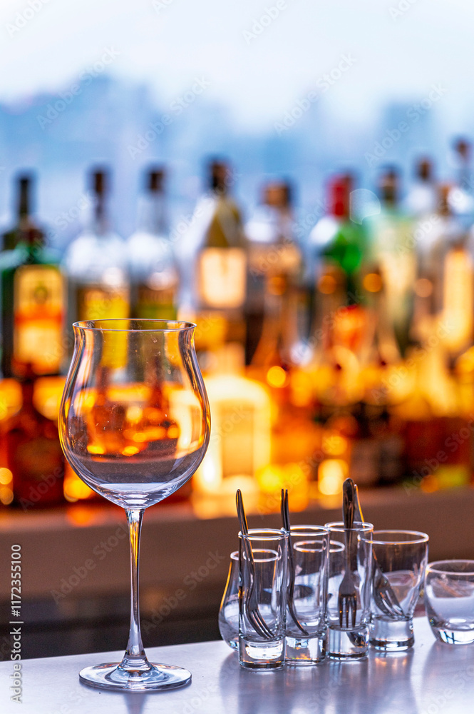 Wine and Drink glasses are arranged in front of drinks counter bar with cityscape background