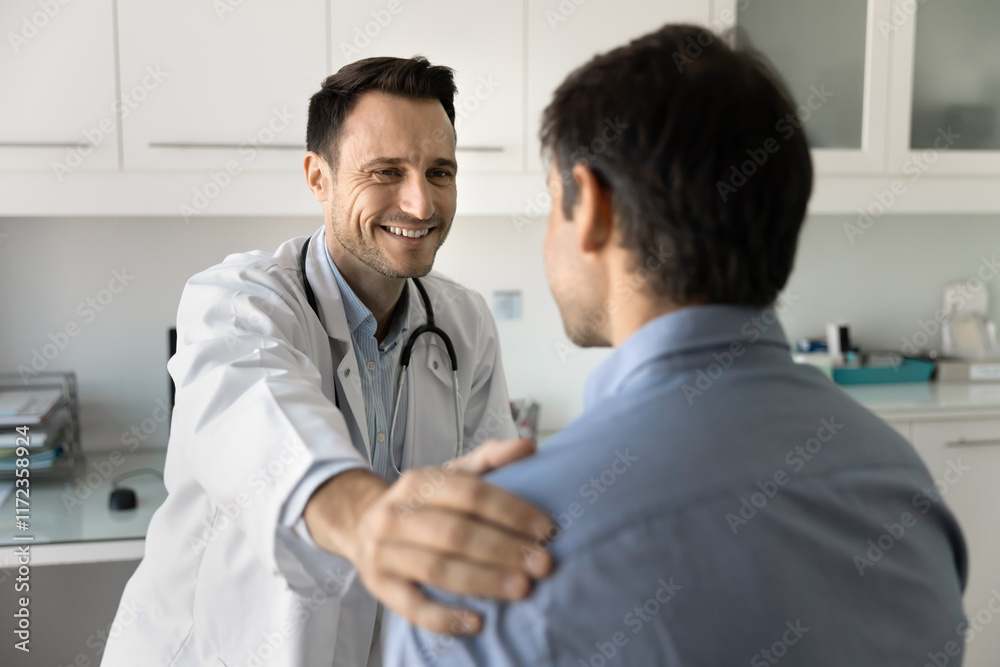 Cheerful male doctor touching shoulder of patient, making supportive friendly gesture, giving support, sympathy, telling good news, optimistic diagnosis, successful therapy results Cheerful male doctor touching shoulder of patient, making supportive friendly gesture, giving support, sympathy, telling good news, optimistic diagnosis, successful therapy results