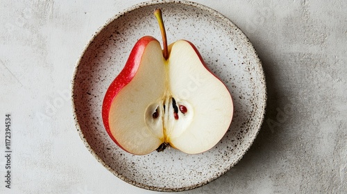 Halved peeled red pear on a speckled plate showcasing organic healthy food and natural products for culinary use and nutrition concepts photo