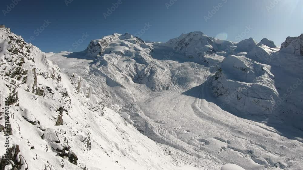 A breathtaking view of snow-covered peaks reaching towards the sky, surrounded by pristine wilderness. The clear blue sky enhances the beauty of this winter landscape, inviting adventure and explorati A breathtaking view of snow-covered peaks reaching towards the sky, surrounded by pristine wilderness. The clear blue sky enhances the beauty of this winter landscape, inviting adventure and explorati