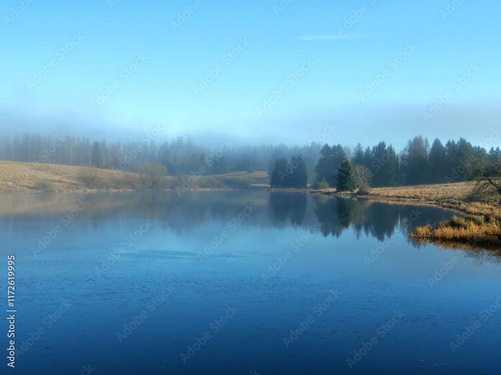 Obraz premium A mystical mining pond in the Harz. Fog, reflections, and horizons in winter create an enigmatic atmosphere, perfect for diverse themes.