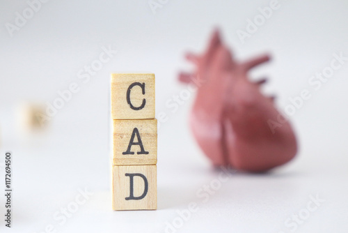 Coronary Artery Disease abbreviaiton. CAD word written on wooden cubes isolated with heart on white background with copy space.  Concept of cardiology illness. photo