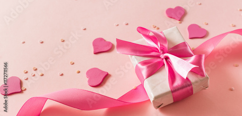 Pink hearts and gift box with ribbon on a light pink background