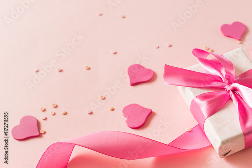 Pink hearts and gift box with ribbon on a light pink background