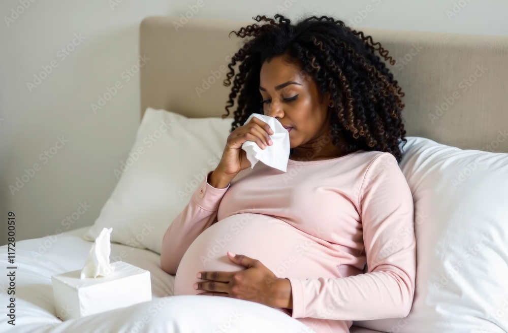 Pregnant african female adult sneezing in bed with tissue box Pregnant african female adult sneezing in bed with tissue box