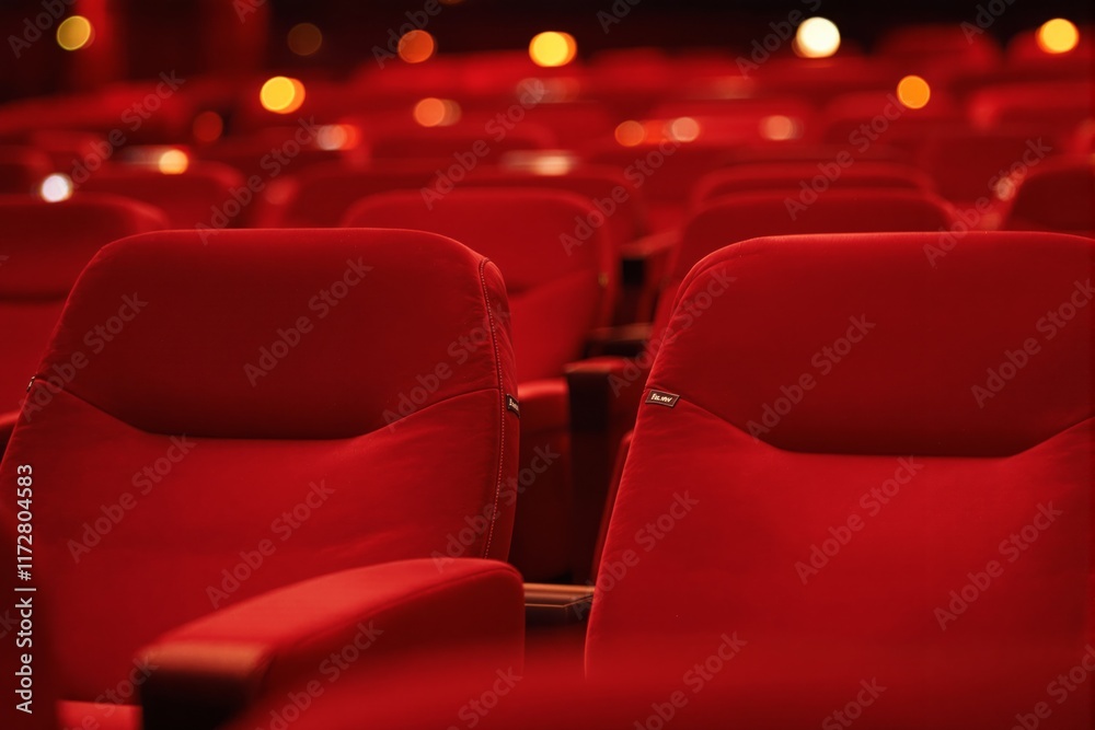 Obraz premium Close-up of red theater seats, warm bokeh lights in the background, cinematic ambiance, on a dark background, concept of entertainment. Ai generative