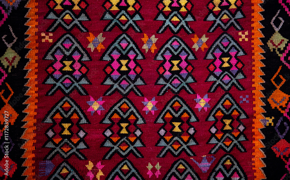Traditional rug with intricate geometric patterns in red, orange, yellow, pink, and black. Symmetrical shapes and vibrant colors create a rich tapestry design, bordered by bold, contrasting edges. Traditional rug with intricate geometric patterns in red, orange, yellow, pink, and black. Symmetrical shapes and vibrant colors create a rich tapestry design, bordered by bold, contrasting edges.